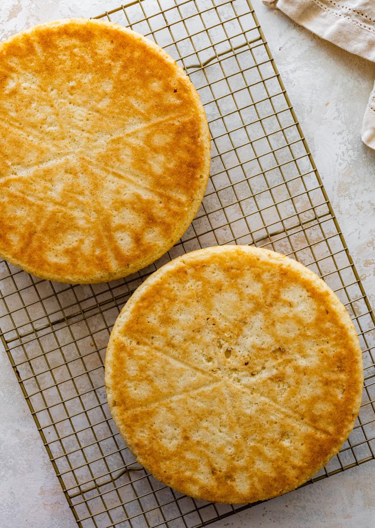 Two round cakes on a cooling rack.