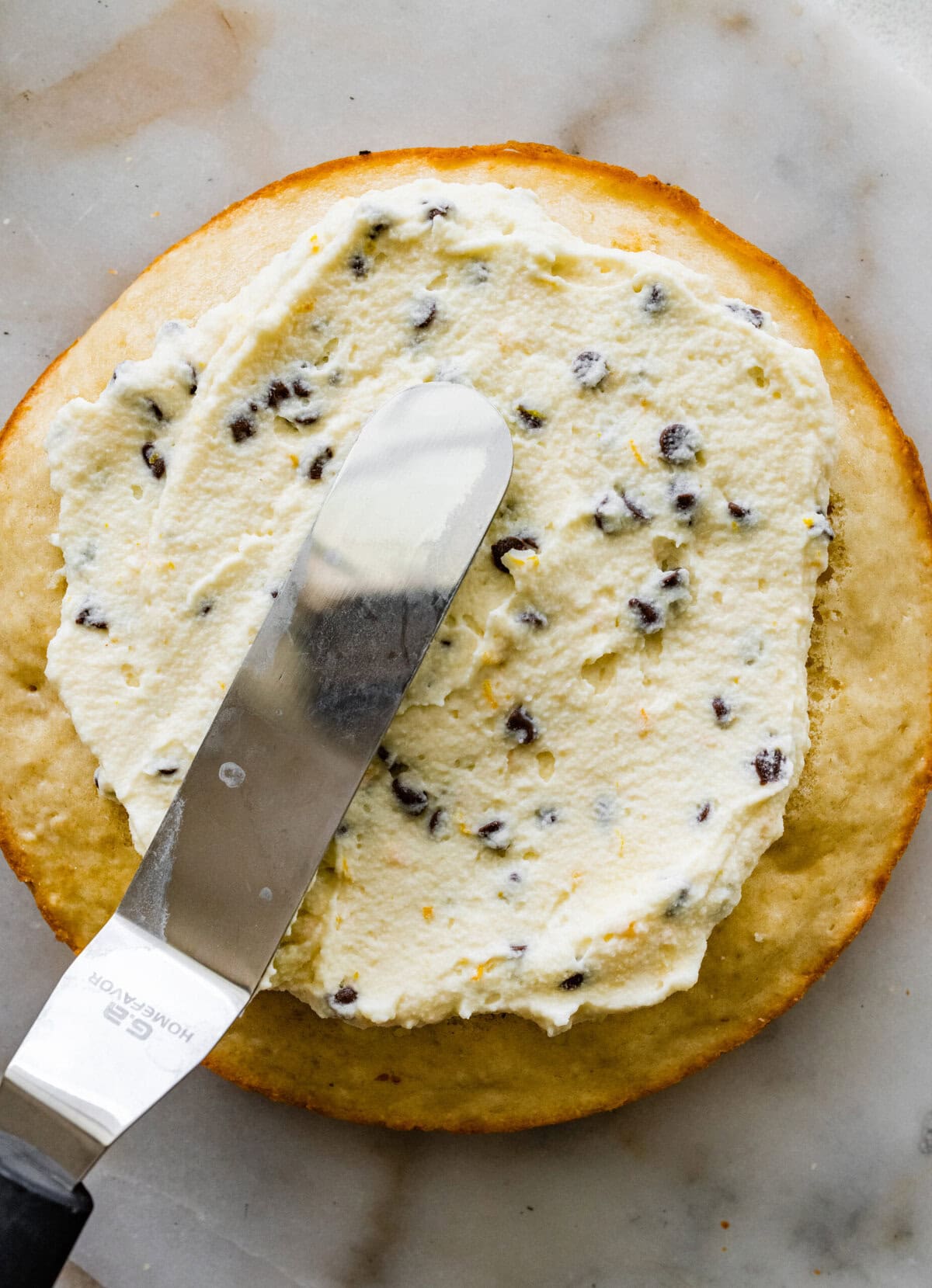 Spreading the cannoli filling in the layers of the cake.