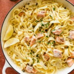 Pasta with salmon and lemon in a white pan.