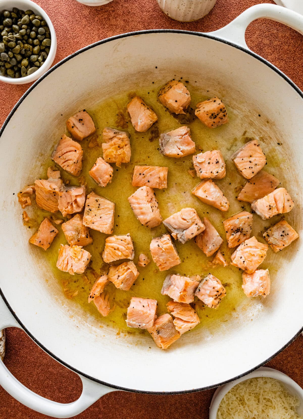 Salmon cooking in a pan with olive oil.