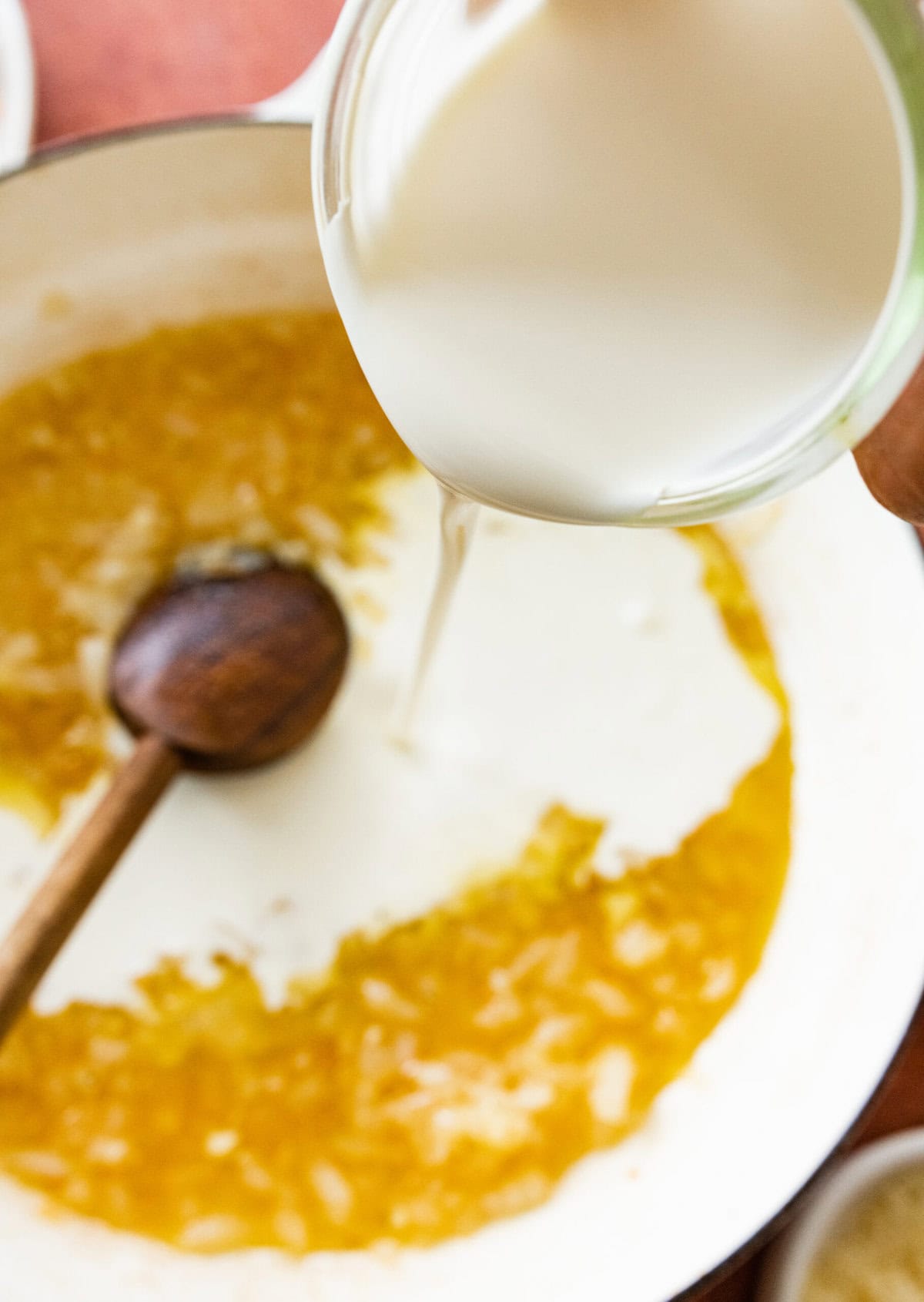Pouring heavy cream into the pan with onions and garlic.