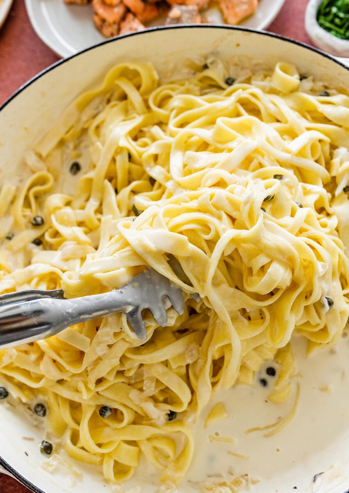 Tossing the creamy sauce with the pasta in the pan.