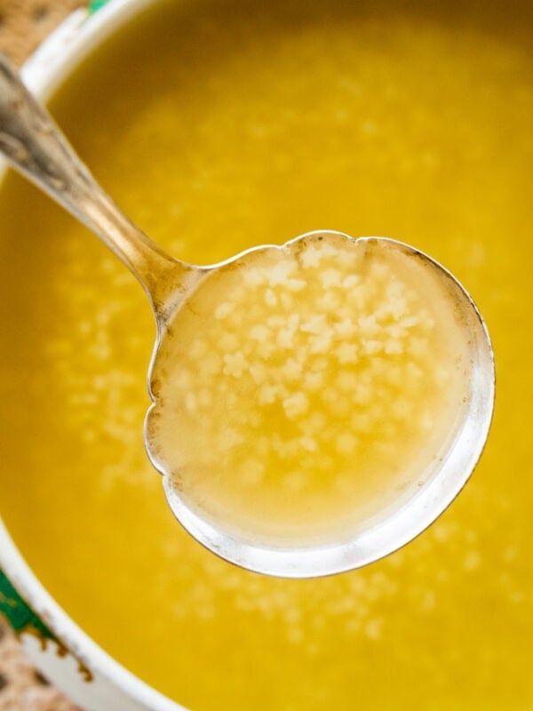 A pot of Italian penicillin soup with a ladle lifting up a bit.
