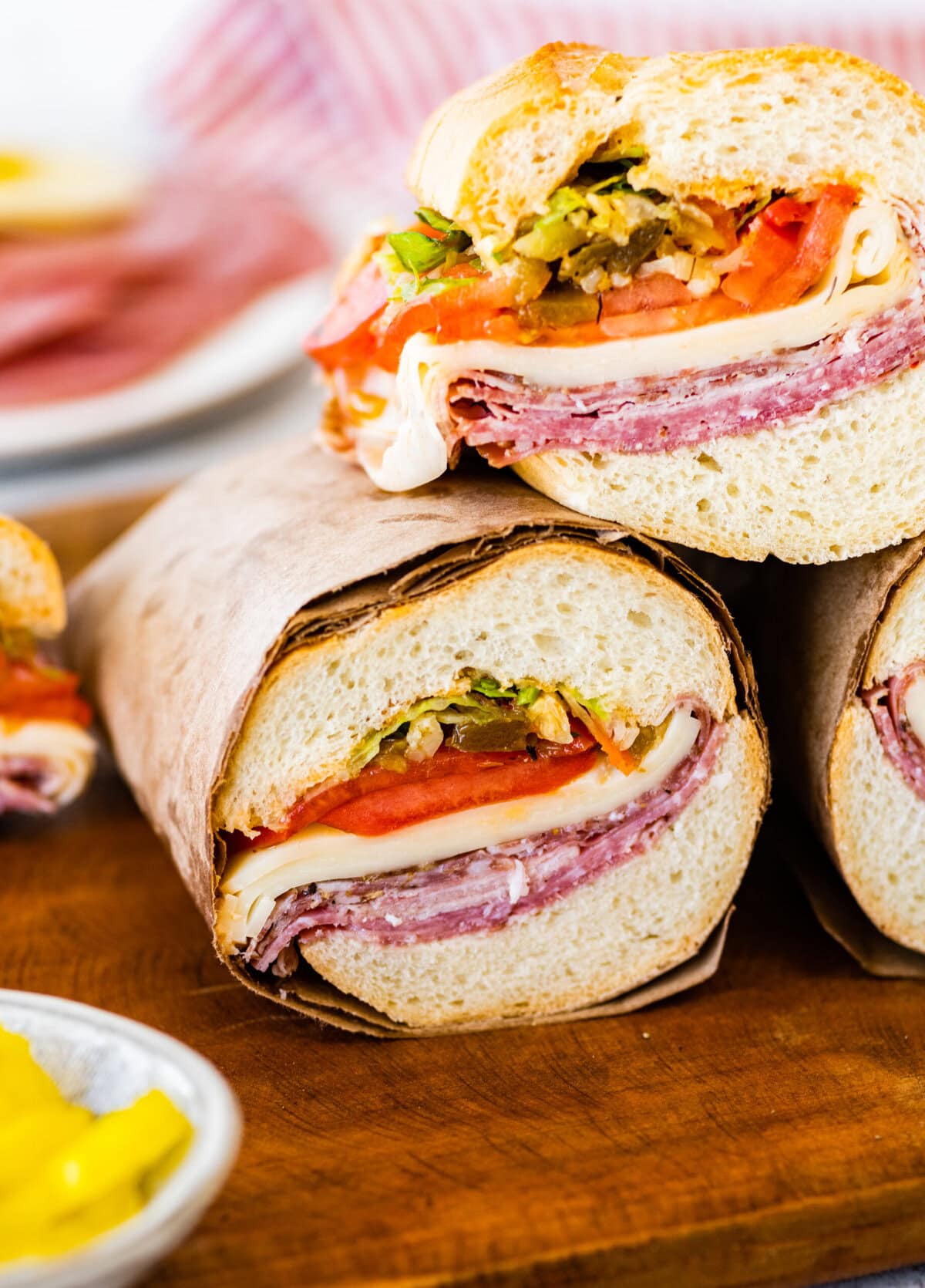 Italian sub sandwiches cut in half with meat, cheese and veggies visible.