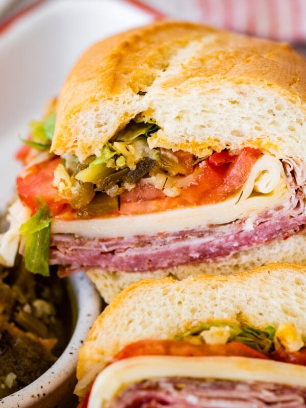 Italian sub sandwiches cut in half with meat, cheese and veggies visible.