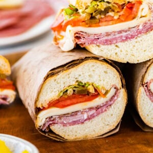 Italian sub sandwiches cut in half with meat, cheese and veggies visible.