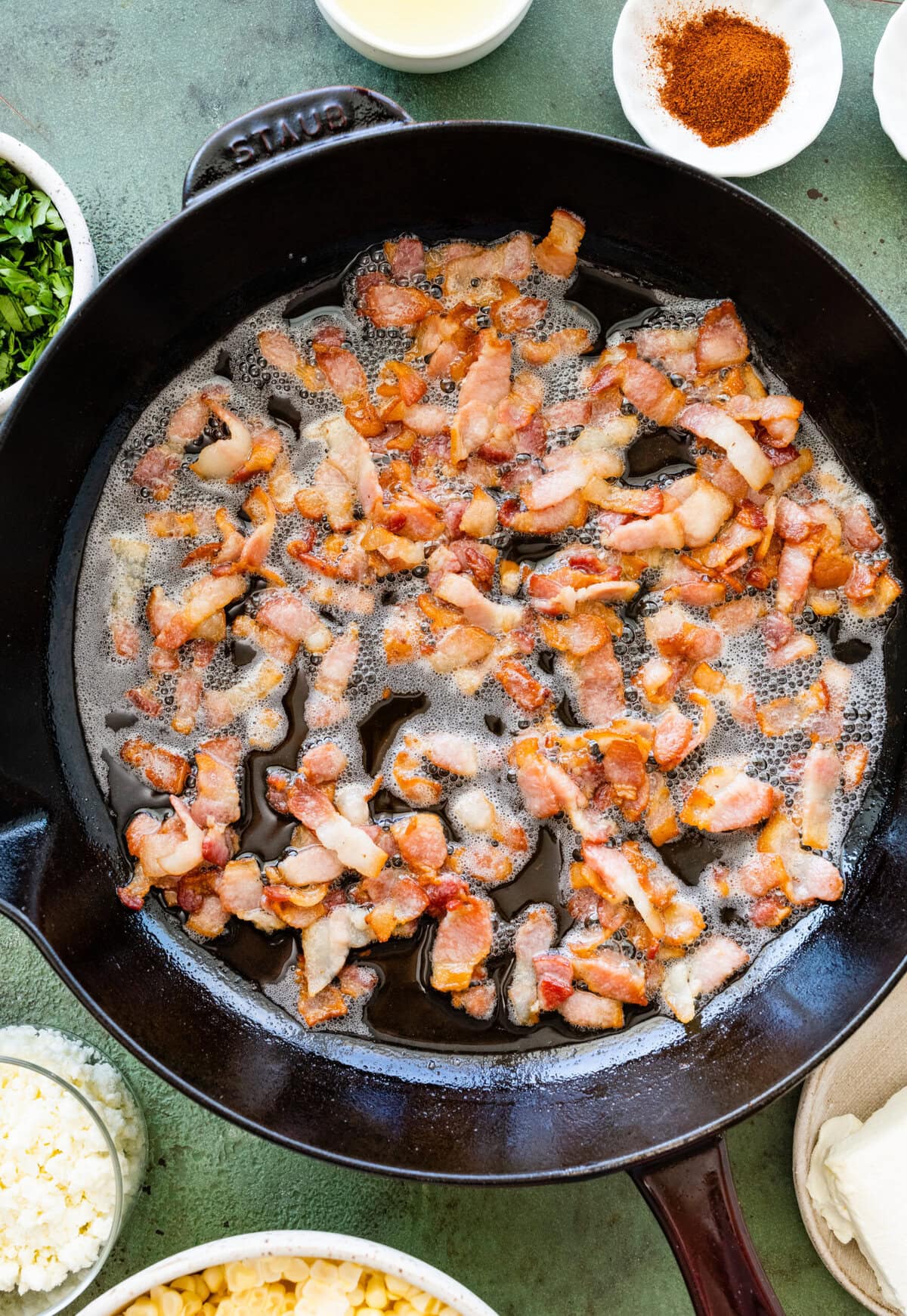 A skillet filled with fried bacon and other ingredients.