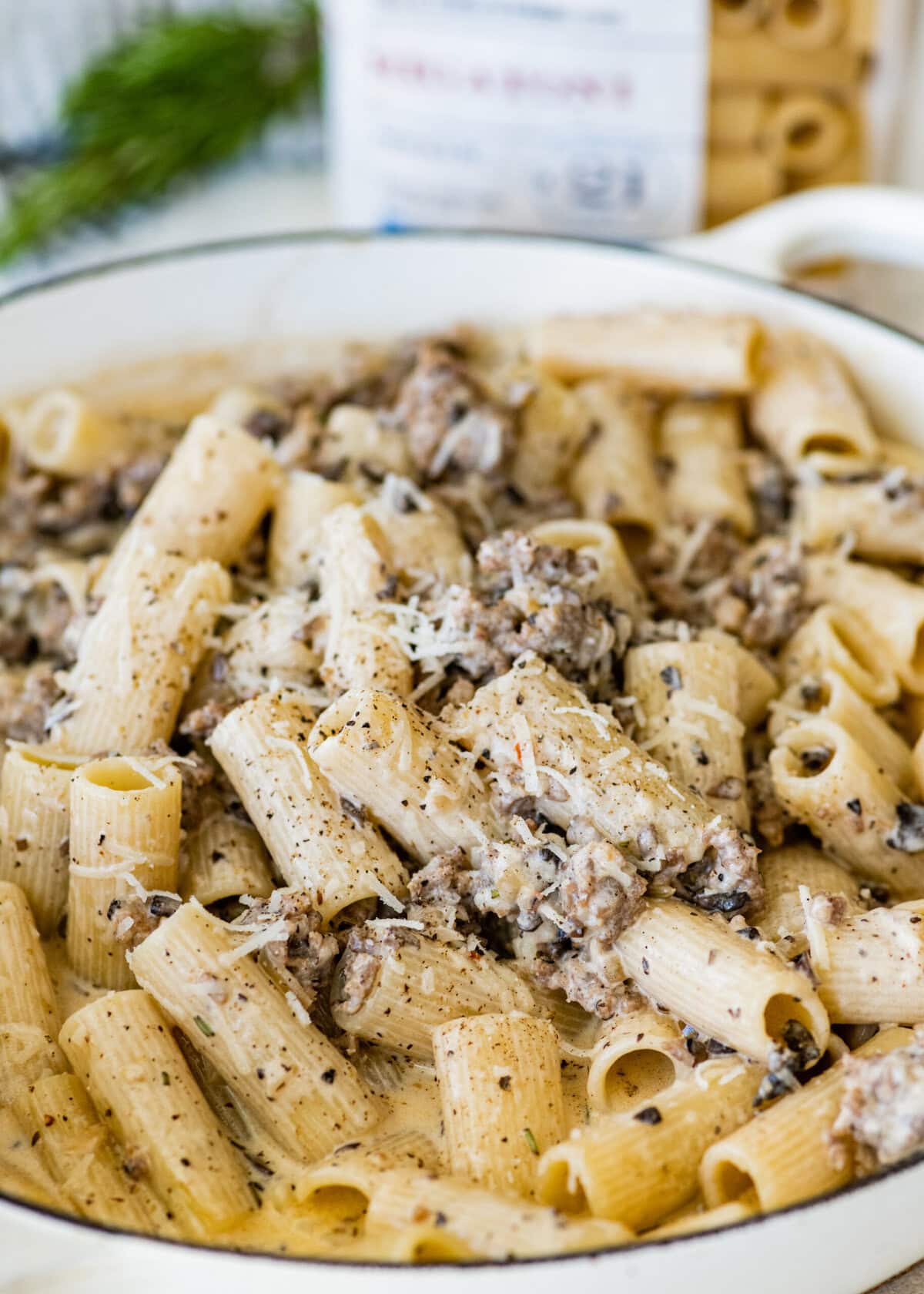 Pasta with Italian sausage and creamy sauce and cheese in a pan.
