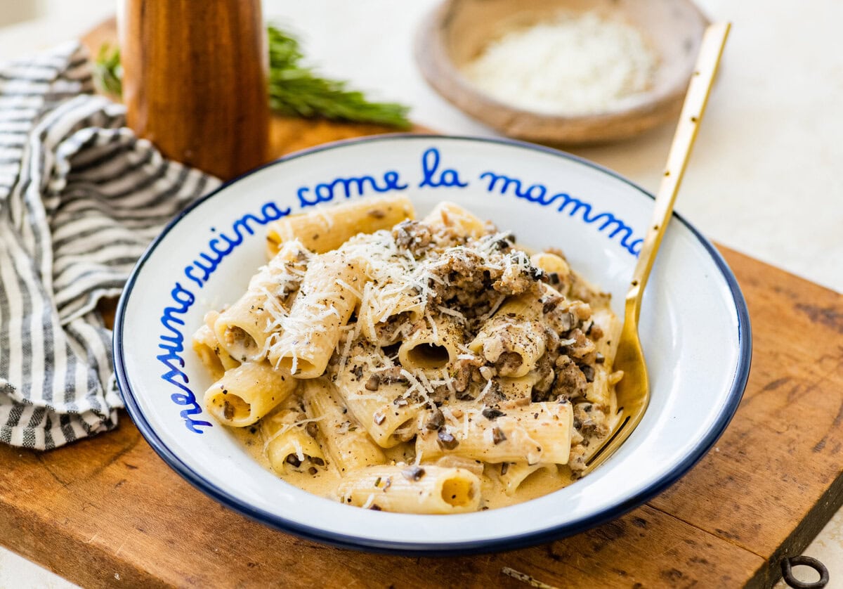 pasta alla norcina (creamy sausage pasta) in a white and blue pasta bowl with extra cheese on top.