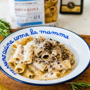 pasta alla norcina (creamy sausage pasta) in a white and blue pasta bowl with extra cheese on top.