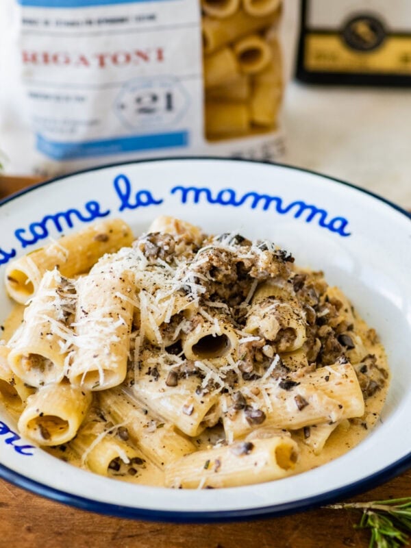 pasta alla norcina (creamy sausage pasta) in a white and blue pasta bowl with extra cheese on top.