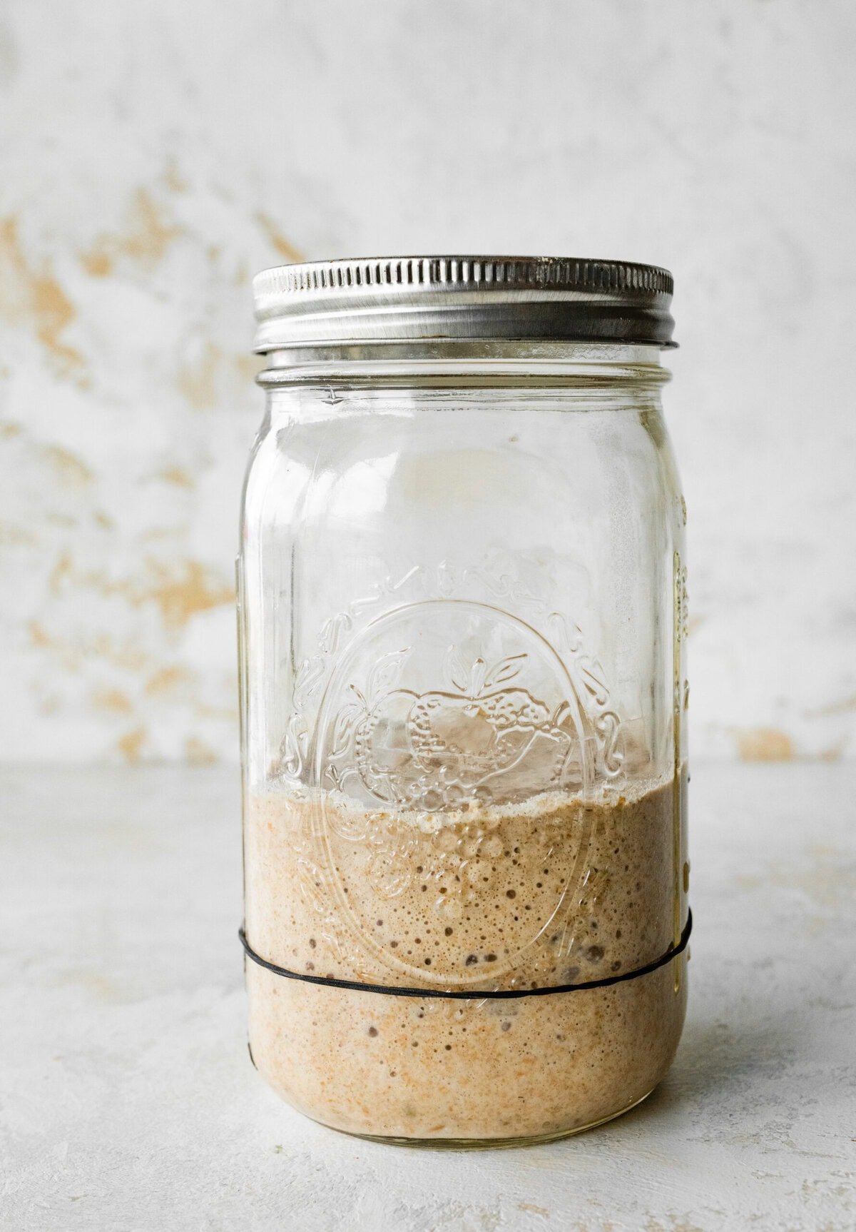 A mason jar filled with a homemade sourdough rye starter.