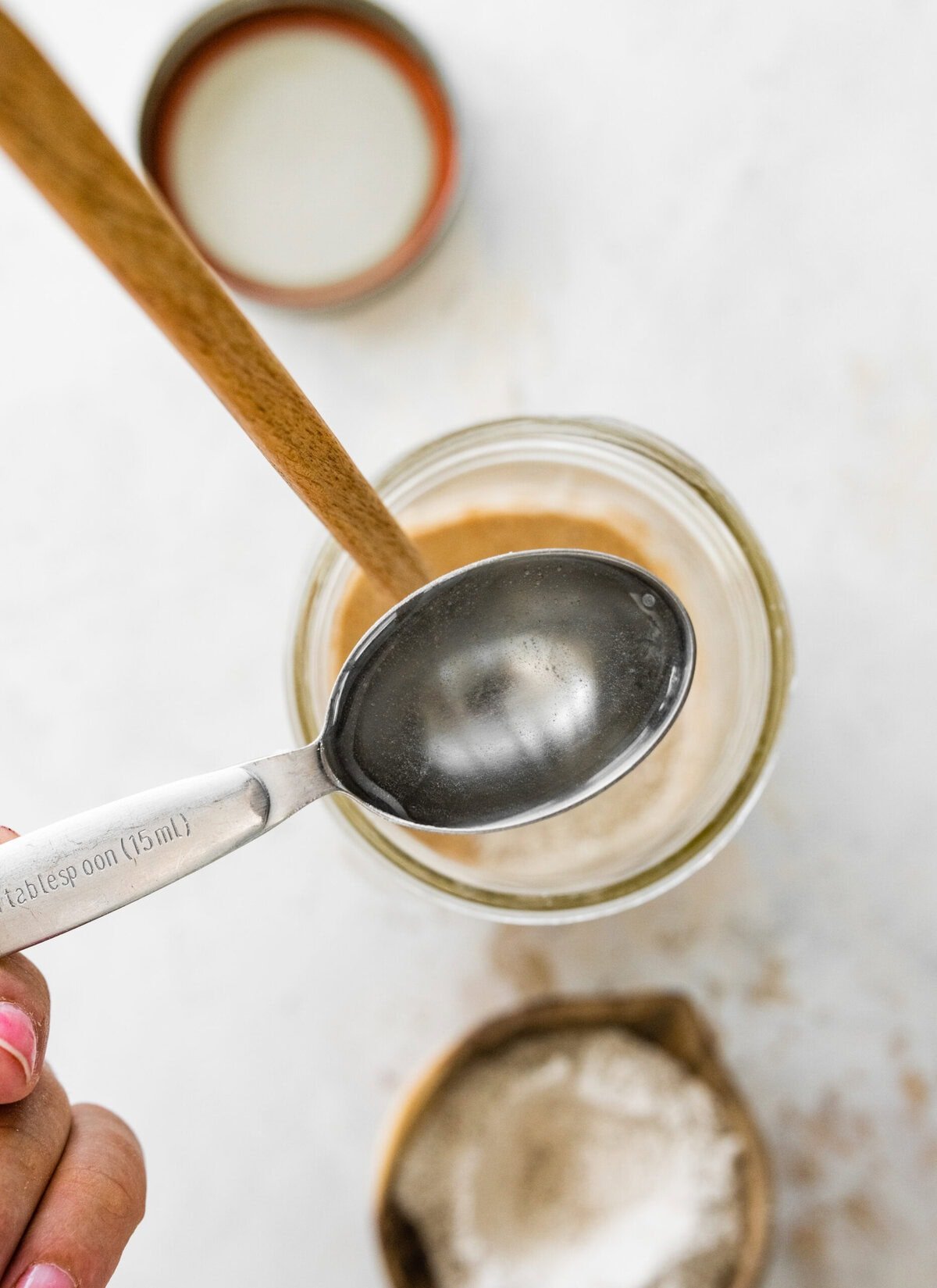 A spoon is being used to stir the ingredients in a jar.