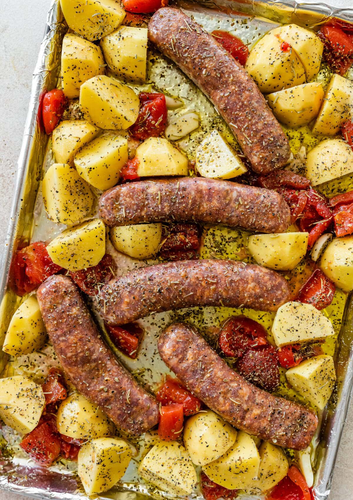 Tomatoes are added to the pan with the sausages and potatoes and herbs sprinkled on top.