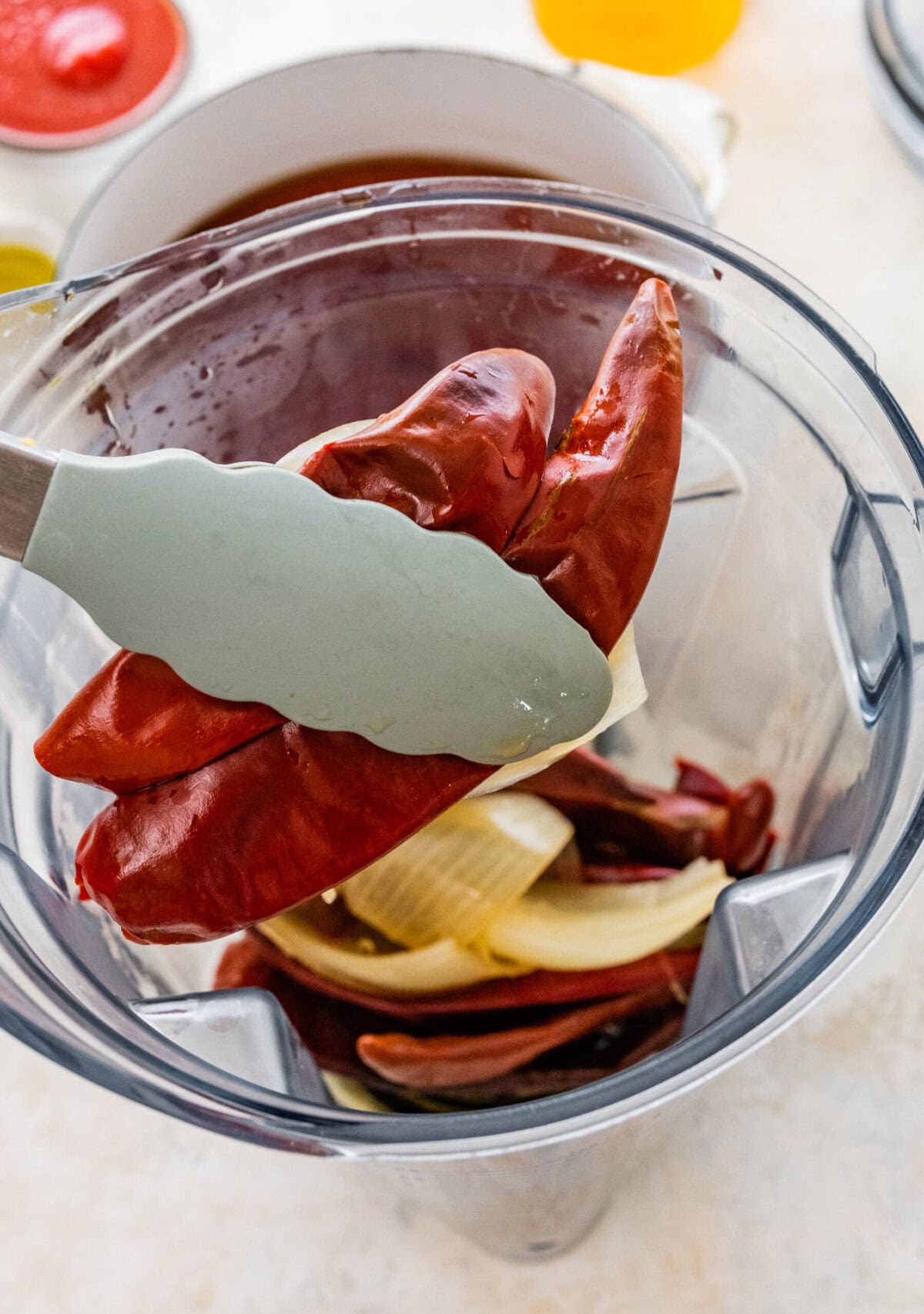 A blender with peppers and onions in it for the homemade red enchiladas sauce.