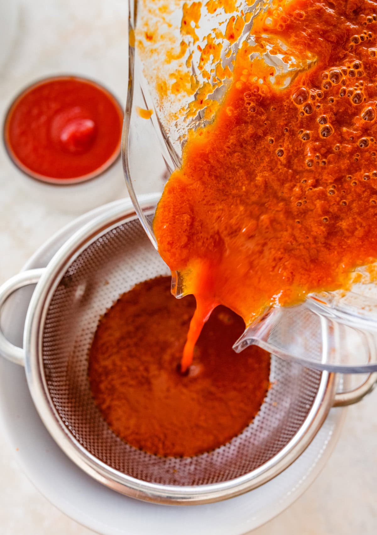 straining the red enchilada sauce from the blender.