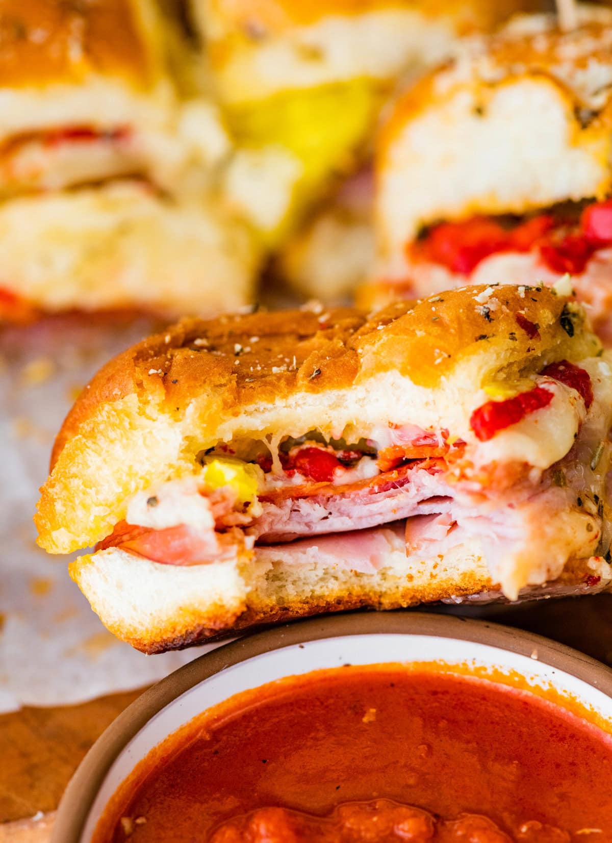 An Italian slider with a side of marinara sauce. A bite taken out of it.