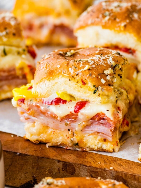 A person holding a sandwich with ham, cheese and peppers.