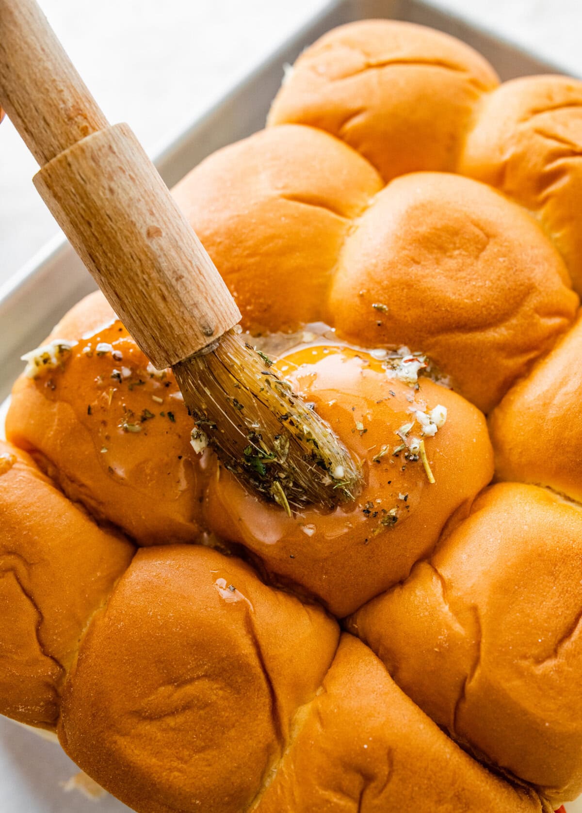 Brushing the garlic butter on top of the Italian slider buns.