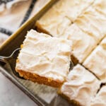 one square of a pumpkin bar with cream cheese frosting held by a cake spatula.