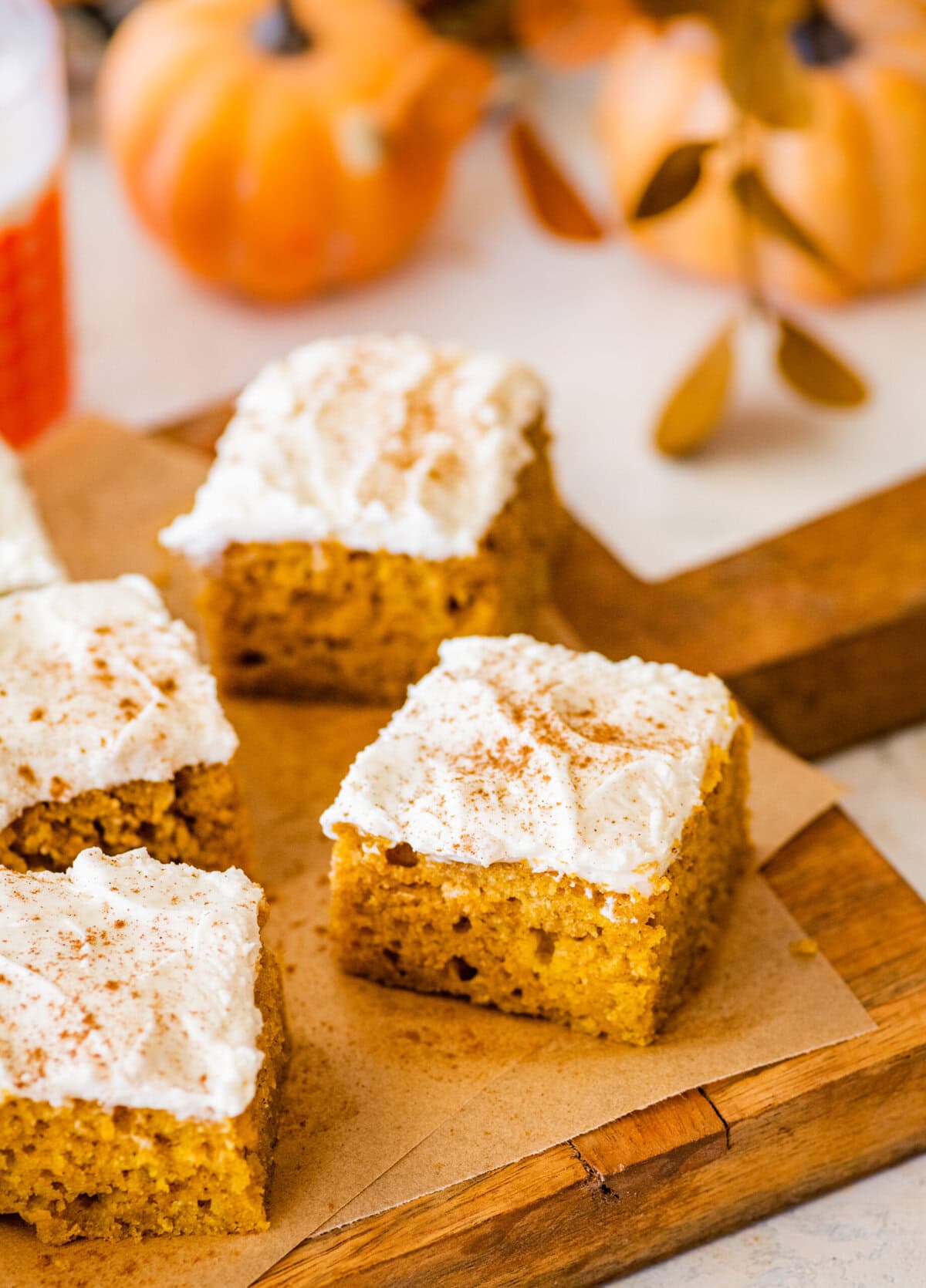 pumpkin bar squares on a cutting board with cream cheese frosting on top.