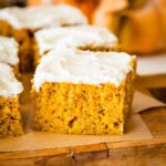 pumpkin bar squares on a cutting board with cream cheese frosting on top.