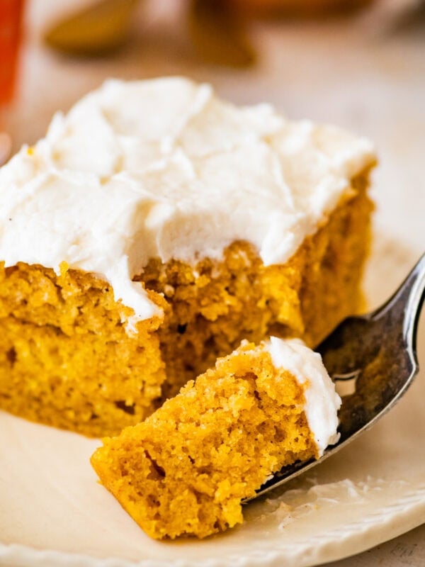 a bite taken out with a fork from the pumpkin bars on a plate.