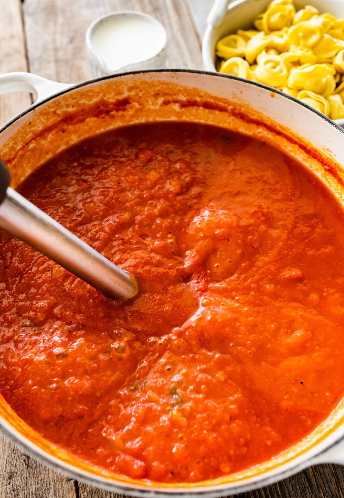 immersion blender in pot blending the tomato soup.