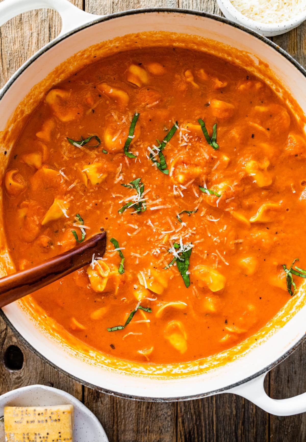pot with the tortellini tomato soup with basil on top.