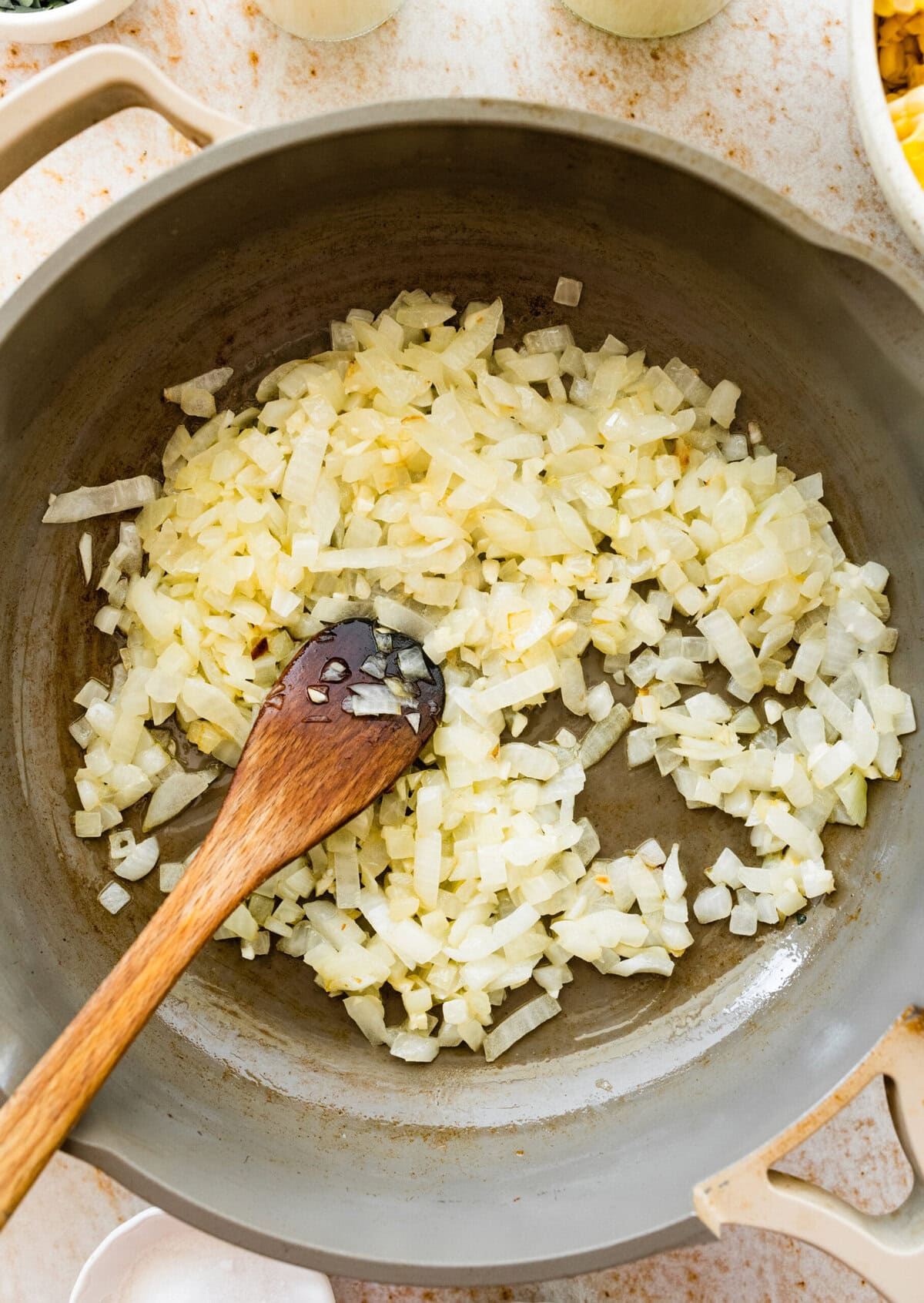 onion cooking in pan with wooden spoon.