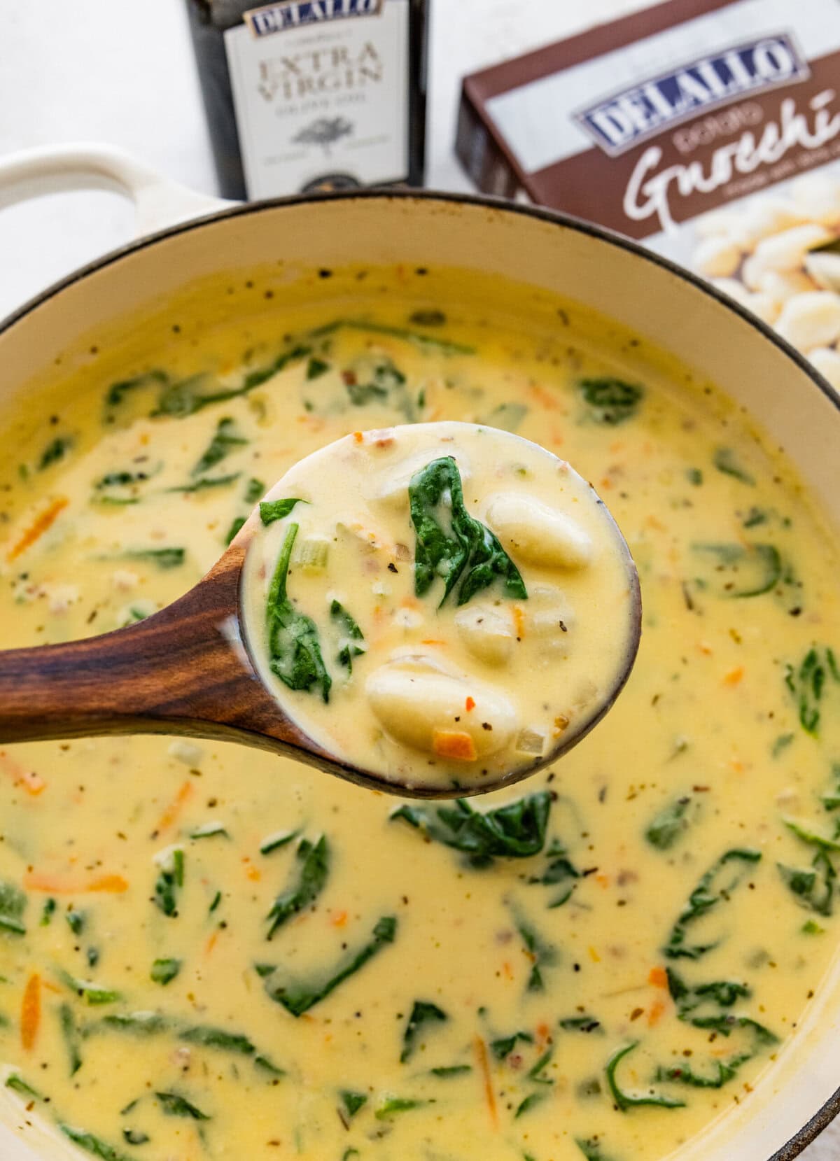 a wooden ladle serving the gnocchi soup over the soup pot.