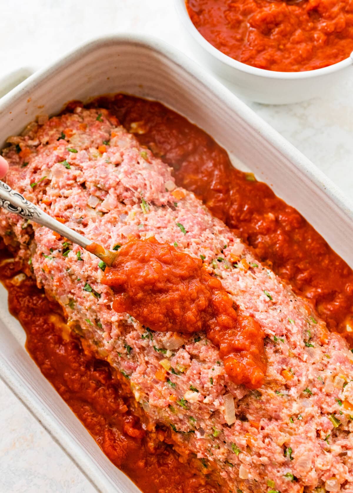 add the meatloaf to the baking dish and top with homemade tomato sauce.