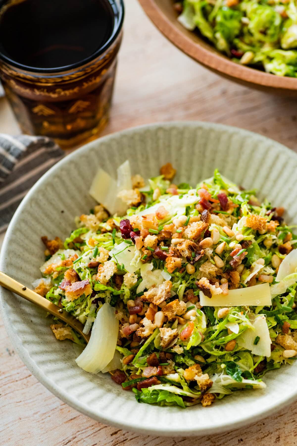 shaved brussels sprouts salad in a single serve white bowl with a fork in it ready to eat.