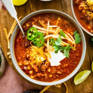 a bowl of taco soup with cheddar cheese, sour cream, and jalapenos. Spoon in the bowl.