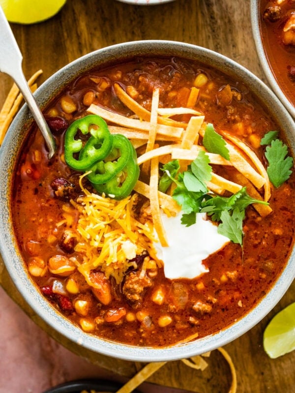 a bowl of taco soup with cheddar cheese, sour cream, and jalapenos. Spoon in the bowl.