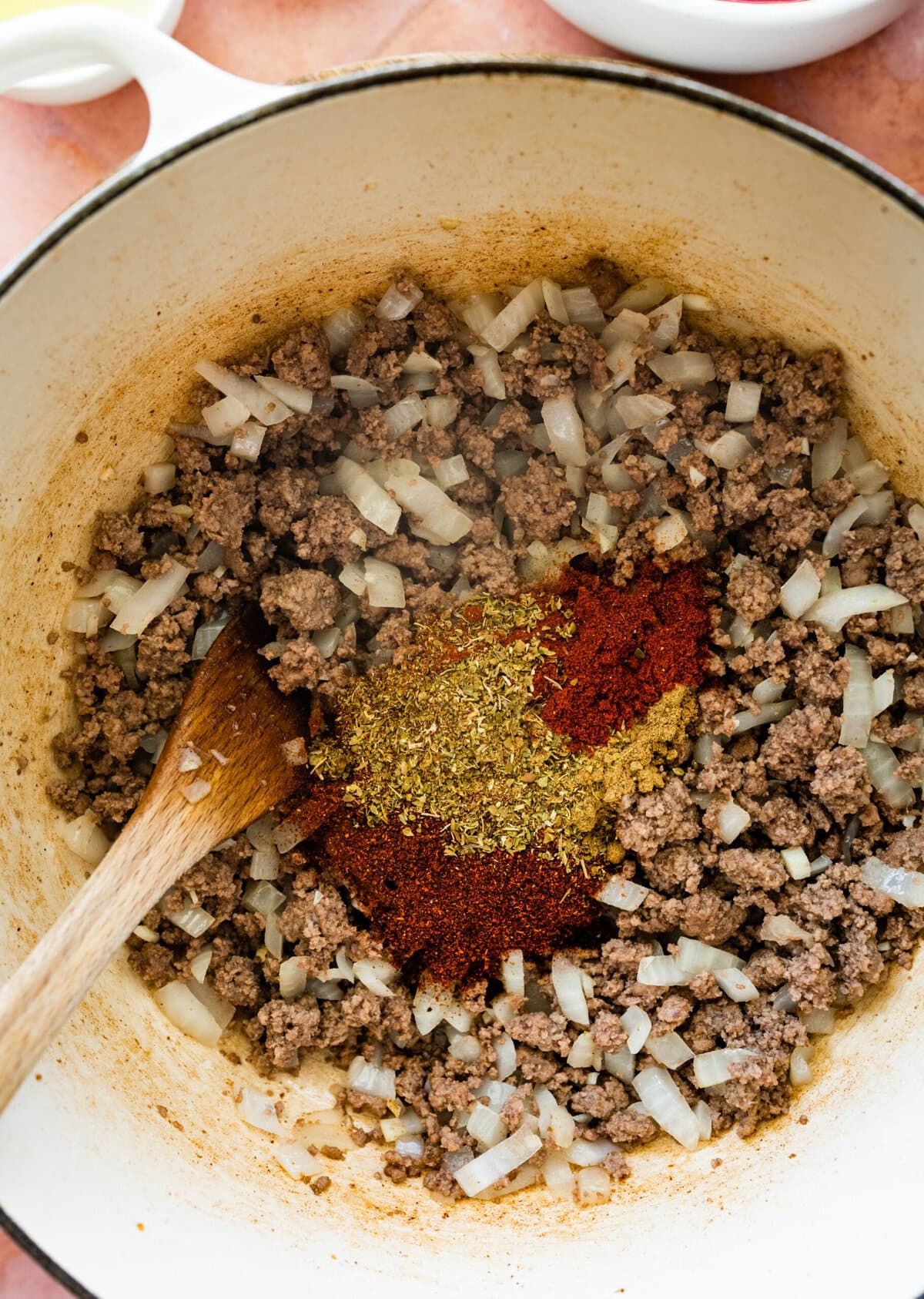 onions and beef in pot with taco seasoning spices.