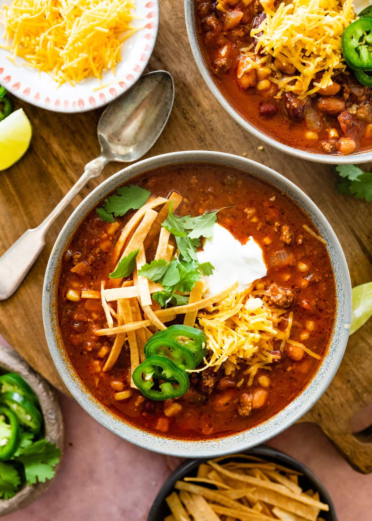 a bowl of taco soup with cheddar cheese, sour cream, and jalapenos.