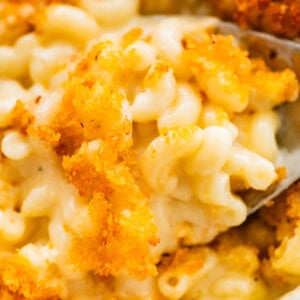 creamy baked mac and cheese in a pan with a serving spoon.