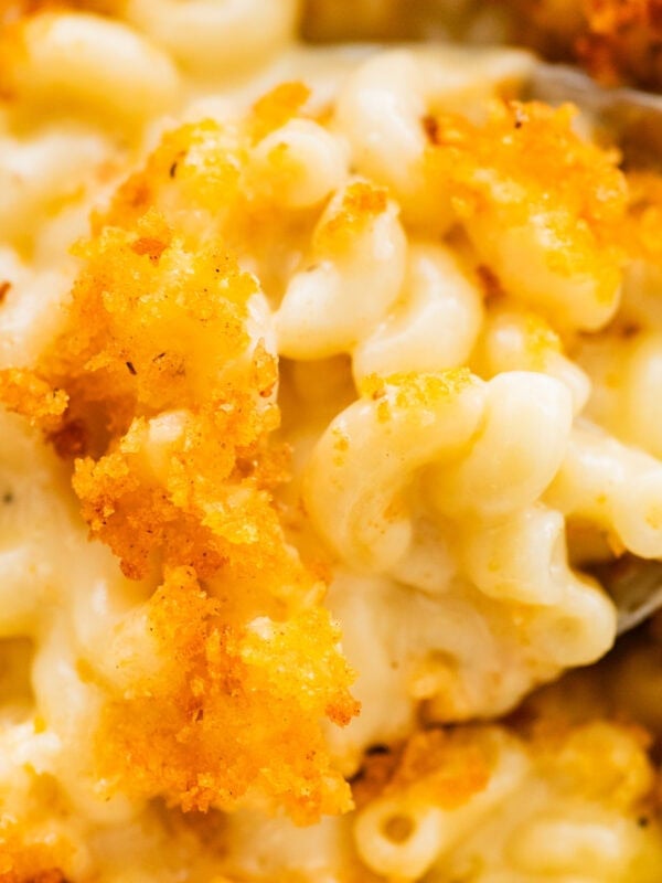 creamy baked mac and cheese in a pan with a serving spoon.