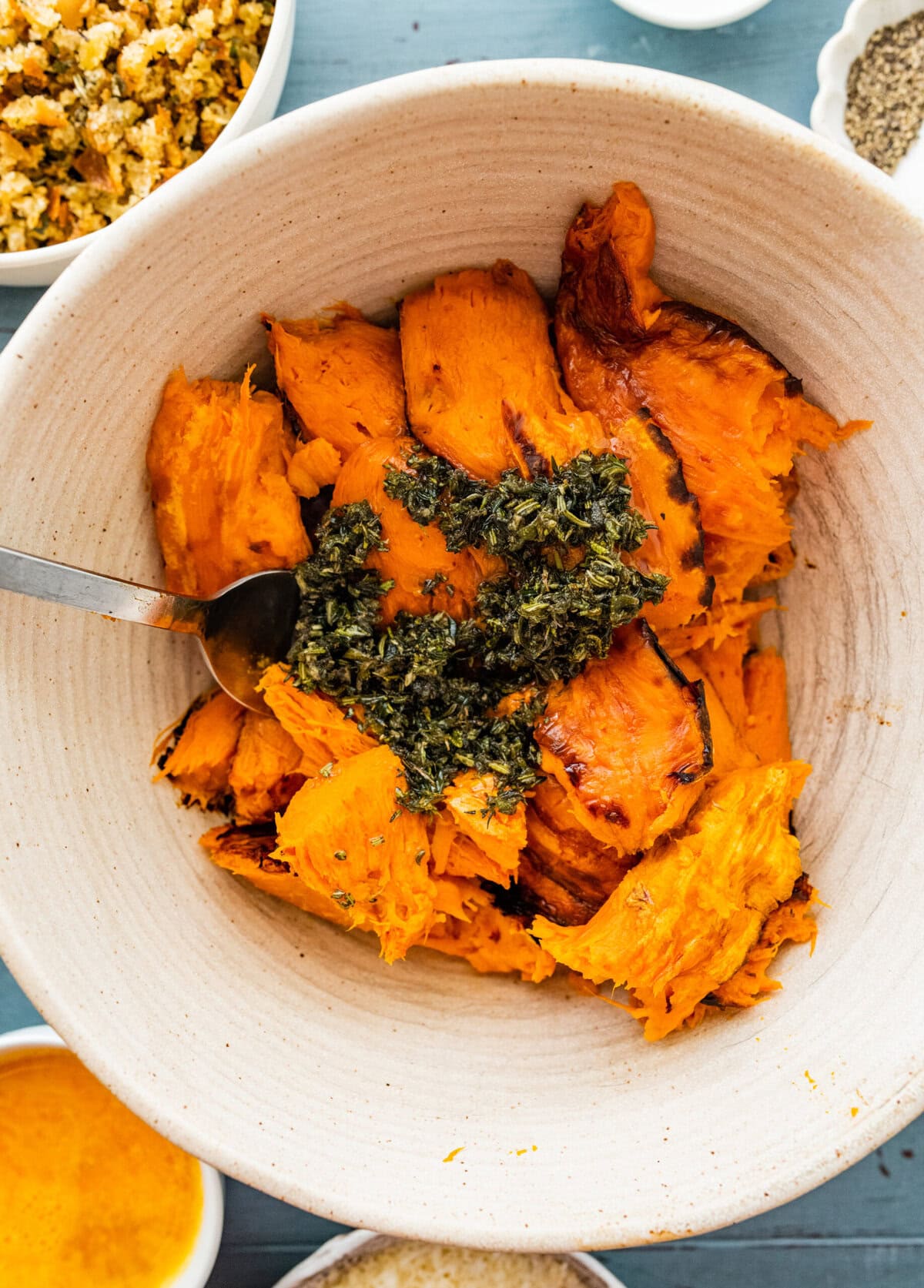 mashed sweet potatoes in a bowl with fresh herbs.