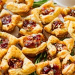 brie bites appetizer on a serving platter with herbs on the side.