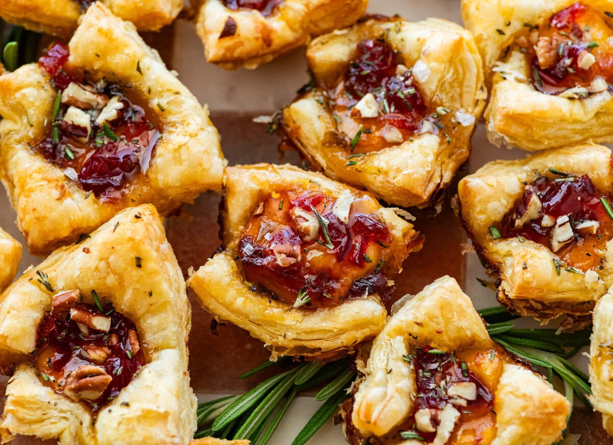 brie bites appetizer on a serving platter with herbs on the side. 