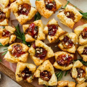 brie bites appetizer on a serving platter with herbs on the side.