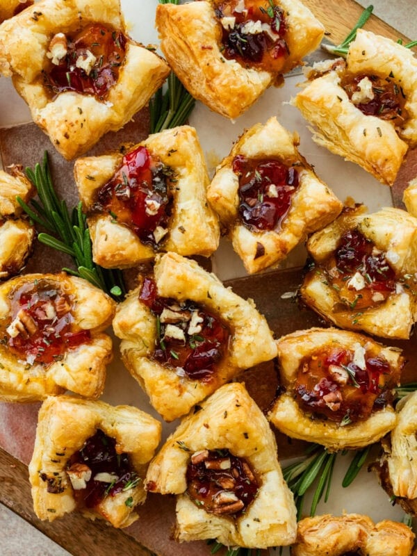 brie bites appetizer on a serving platter with herbs on the side.
