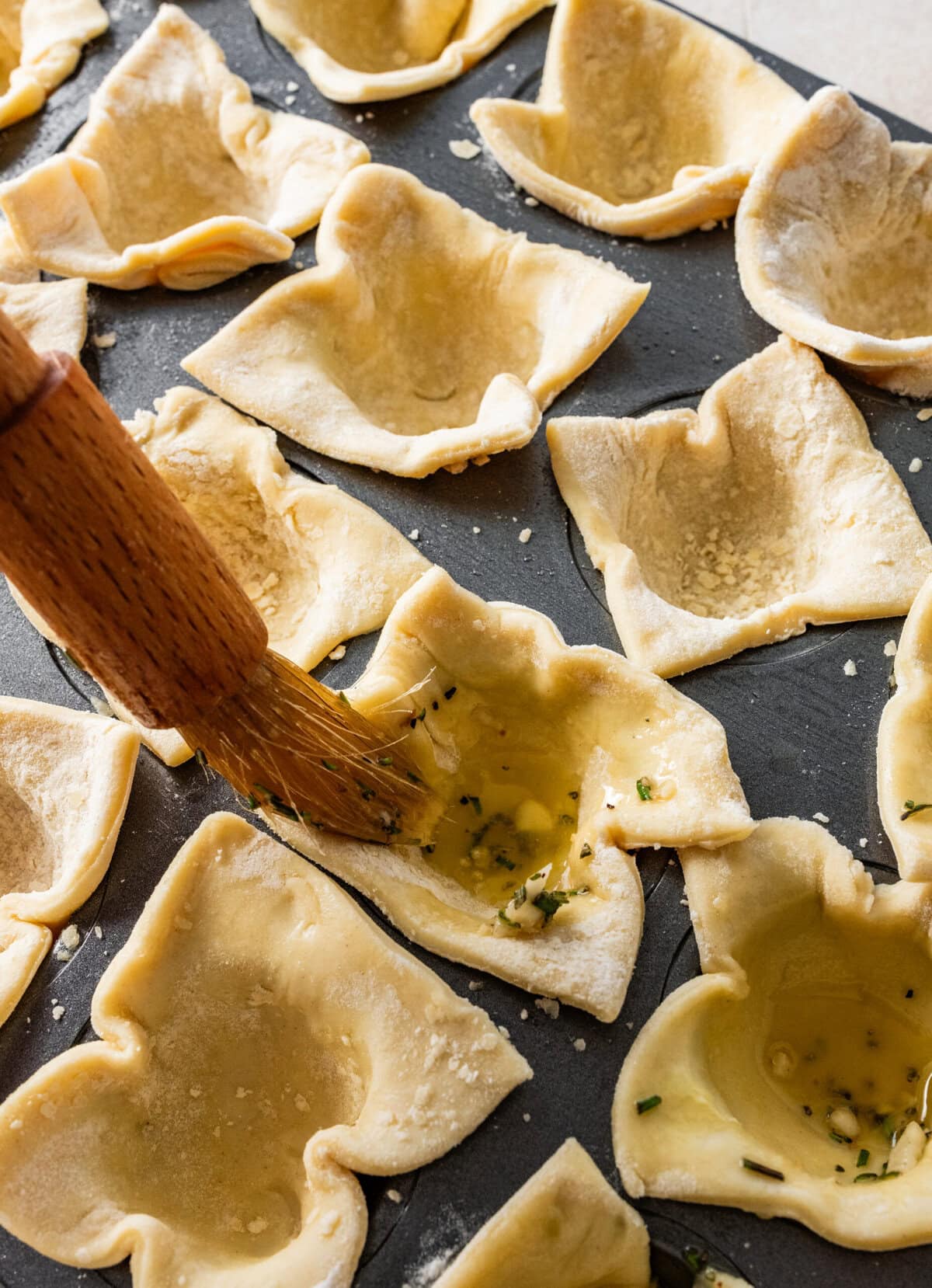 brushing the puff pastry squares with herb butter for the puff pastry bites.