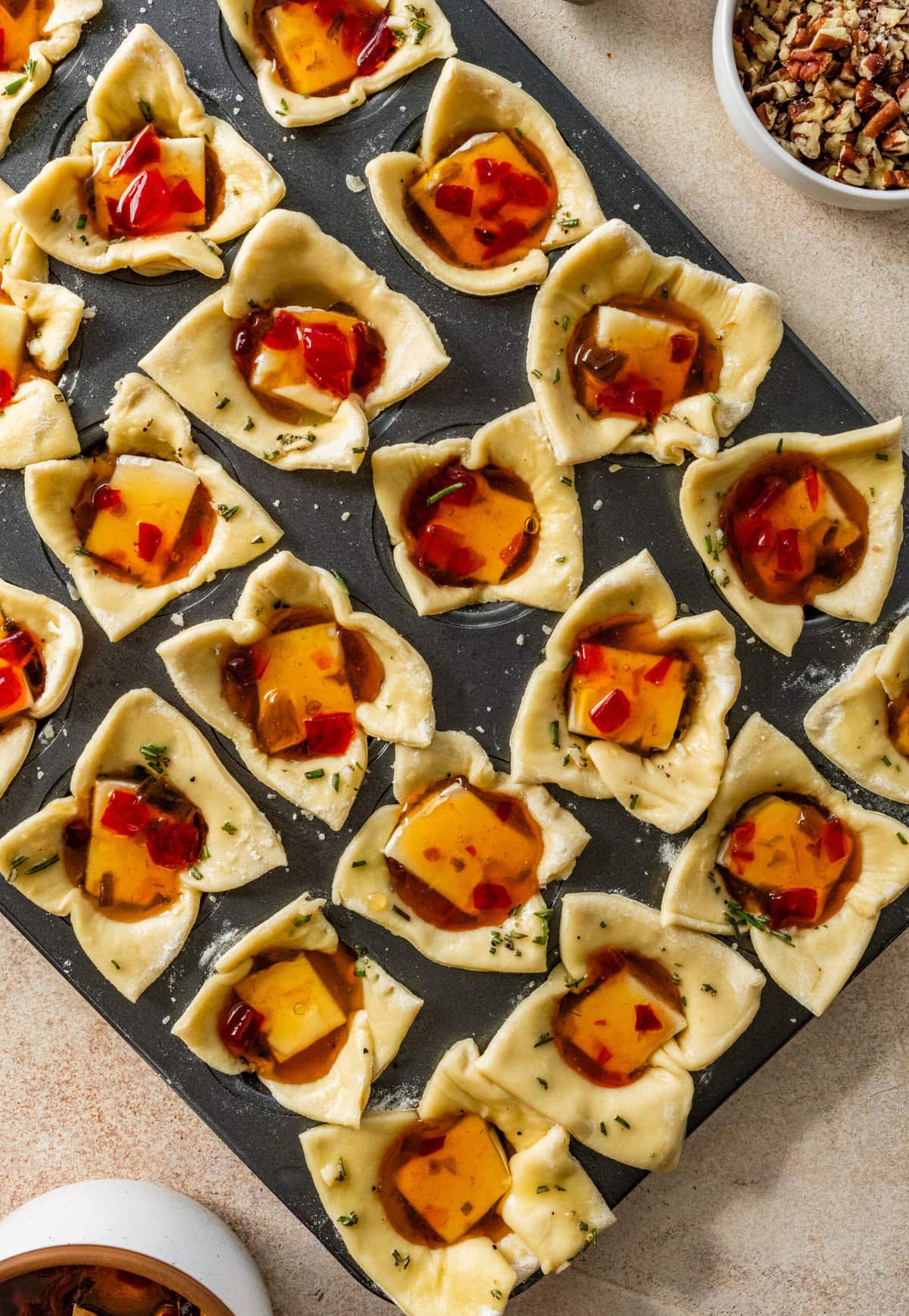 a pan of brie bites in puff pastry in muffin tins ready to bake.