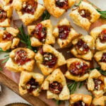 brie bites appetizer on a serving platter with herbs on the side.