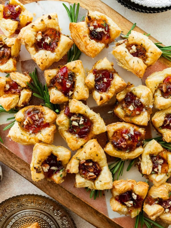 brie bites appetizer on a serving platter with herbs on the side.
