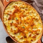 Easy cheesy potatoes in a casserole dish with golden brown bubbly top.