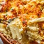 Serving spoon lifting a portion of the cheesy potatoes.